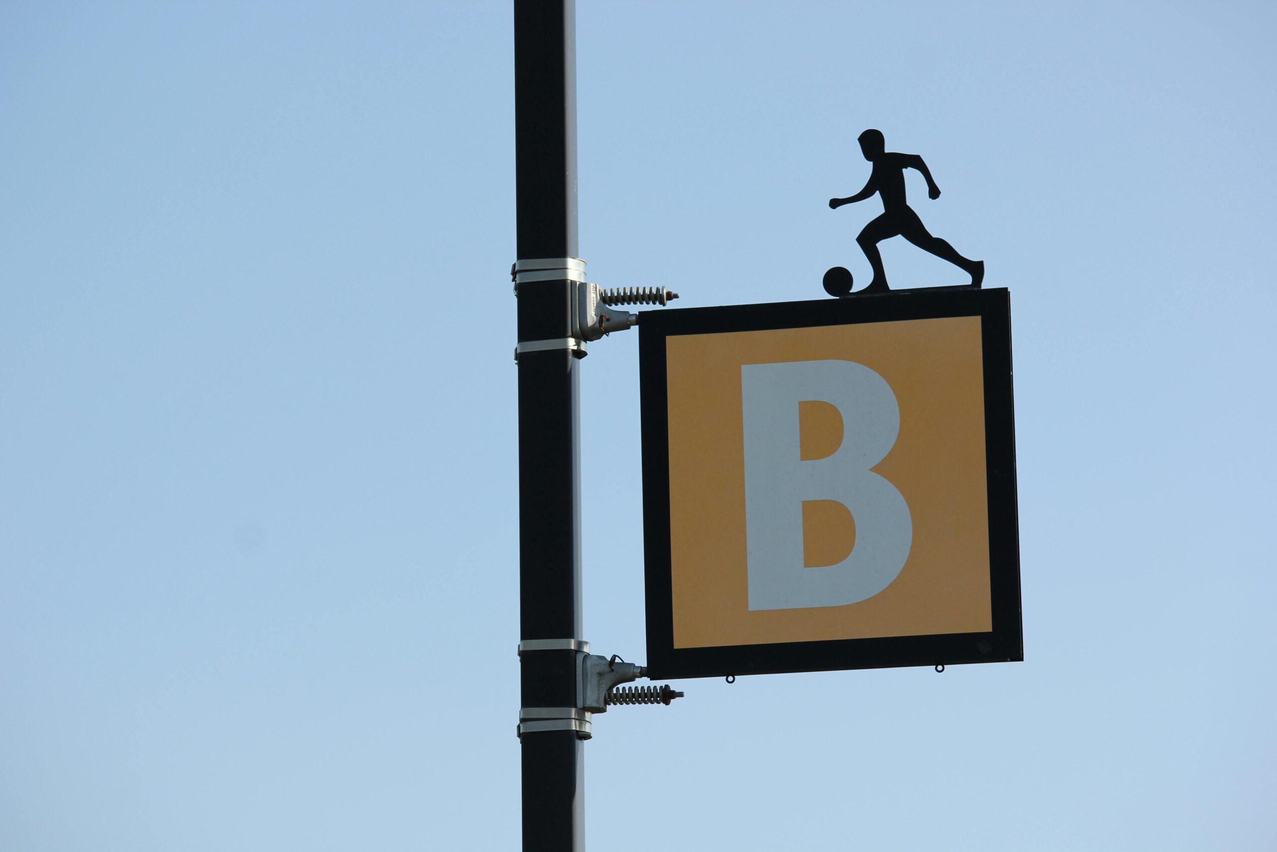 Outdoor sign depicting a soccer player silhouette on letter B background.